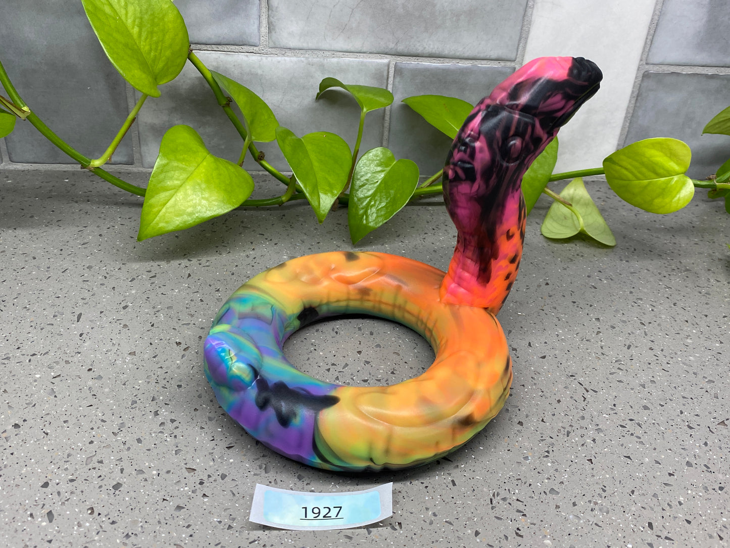a sculpture of a snake on the ground next to a plant