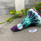 a purple and blue shoe sitting next to a plant