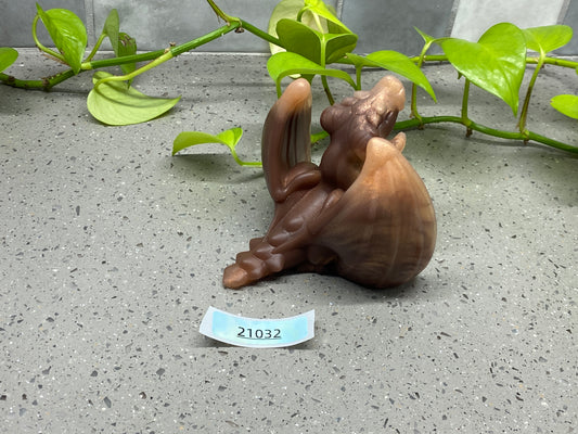 a figurine of a monkey sitting on the ground next to a plant