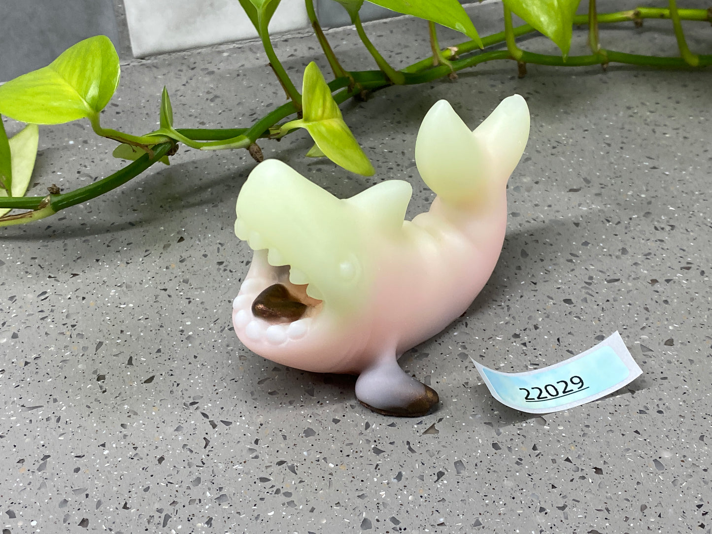 a ceramic figurine of a fish with its mouth open next to a plant