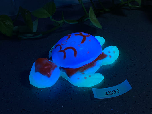 a blue turtle with a red face sitting on the ground