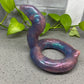 a purple snake shaped object sitting on top of a cement floor