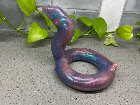 a purple snake shaped object sitting on top of a cement floor