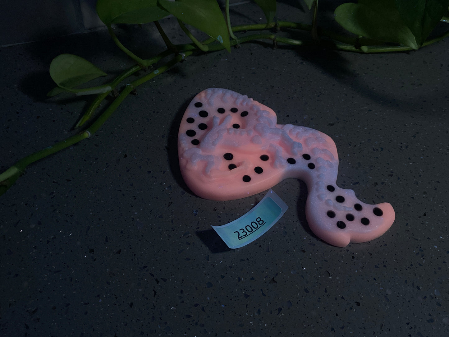 a pink ceramic object with black dots on it