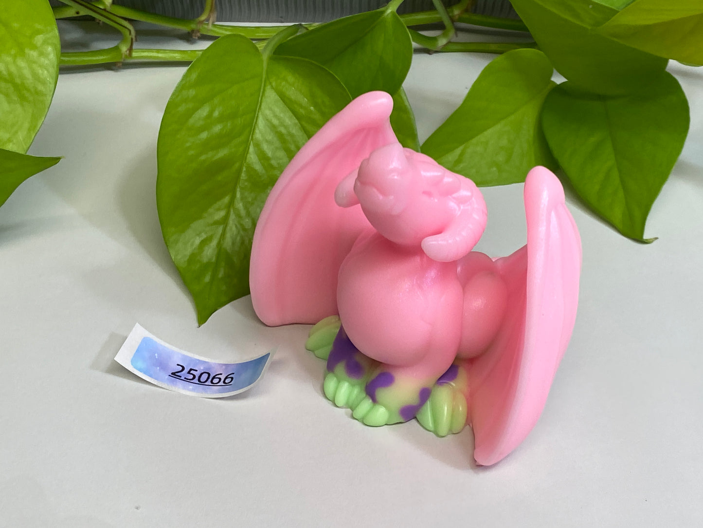 a pink figurine sitting on top of a table next to a plant