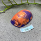 a purple and orange vase sitting on top of a table