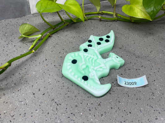 a green broccoli brooch sitting on a table next to a plant