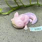 a toy lizard laying on the ground next to a plant