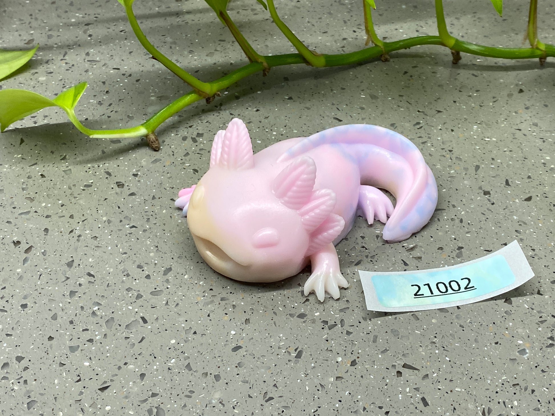 a toy lizard laying on the ground next to a plant