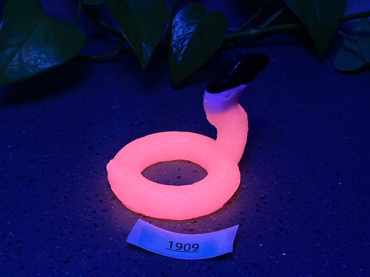a pink ring sitting on top of a table next to a plant