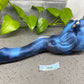 a blue figurine laying on the ground next to a plant