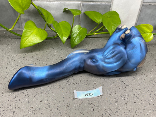 a blue figurine laying on the ground next to a plant