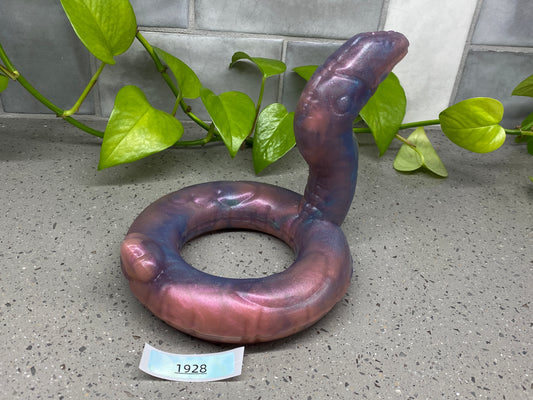 a purple object sitting on the ground next to a plant