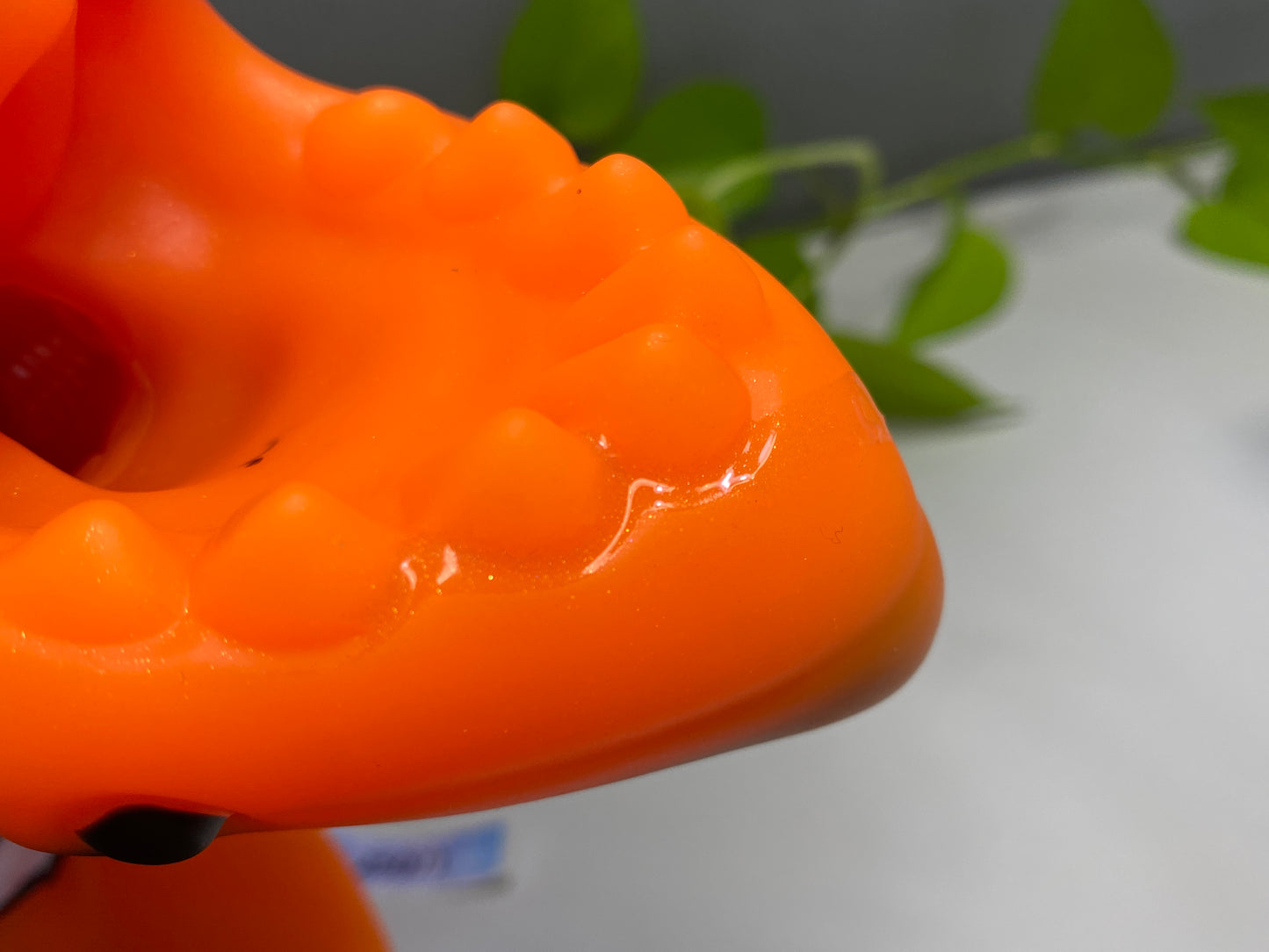 a close up of an orange object with a plant in the background