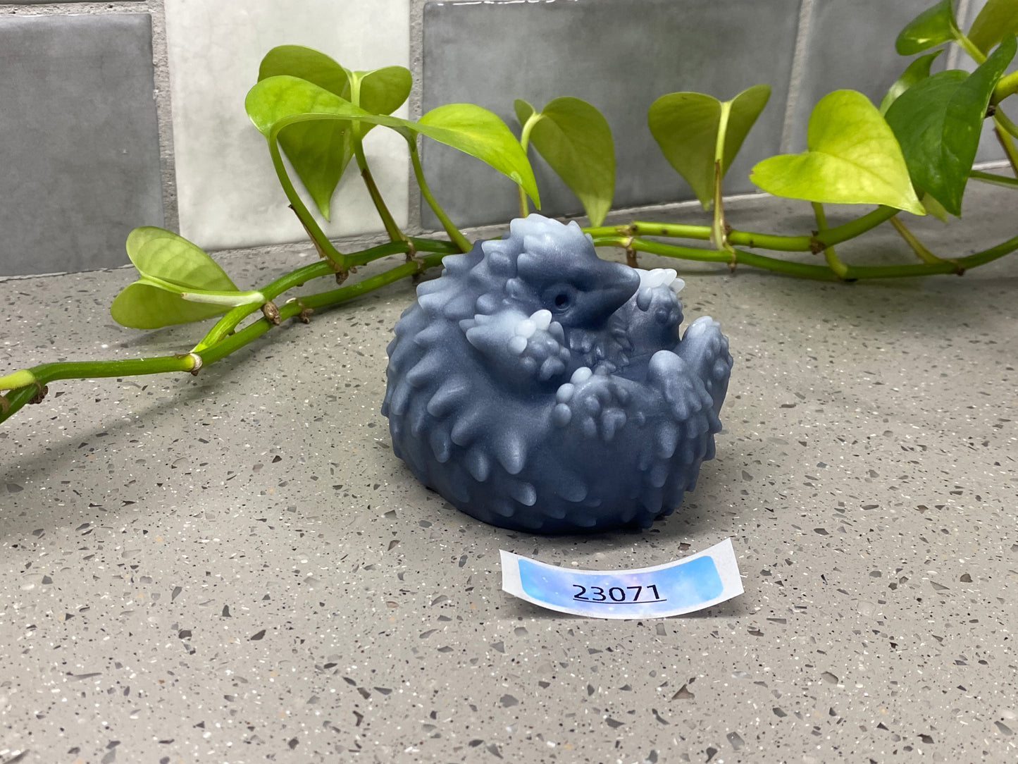 a blue vase sitting on top of a table next to a plant