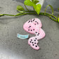 a pink and black object sitting on top of a table next to a plant