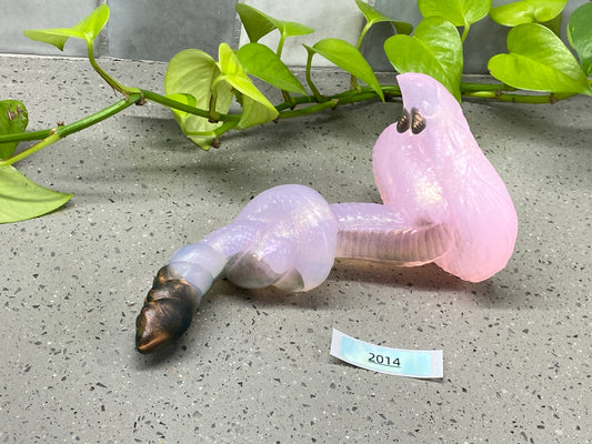 a plastic worm laying on the ground next to a plant