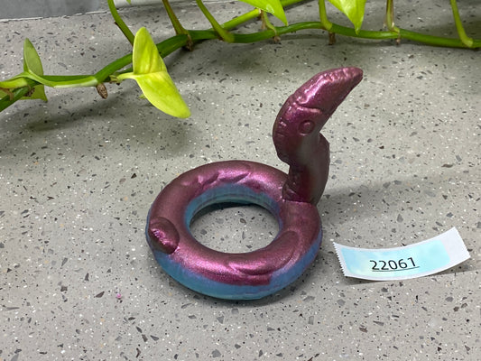 a purple ring sitting on the ground next to a plant