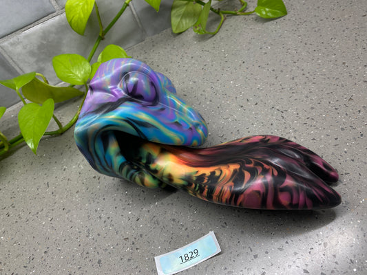 a colorful object sitting on the ground next to a plant
