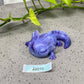 a purple toy lizard sitting on top of a cement floor