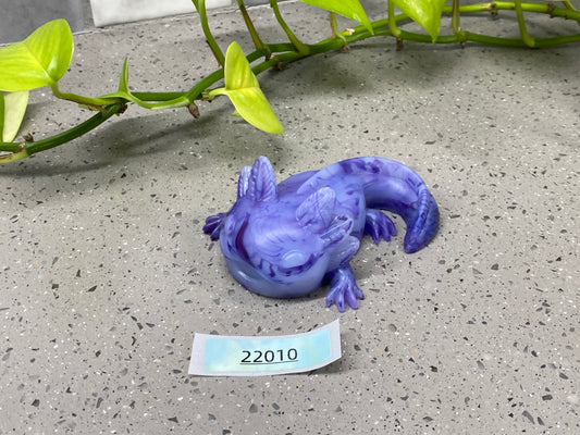 a purple toy lizard sitting on top of a cement floor