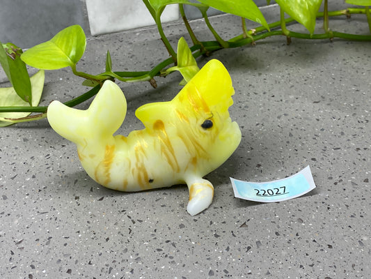 a yellow plastic toy laying on the ground next to a plant