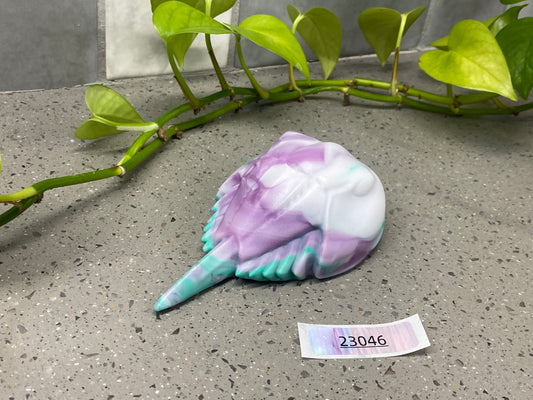 a purple and white shell next to a plant