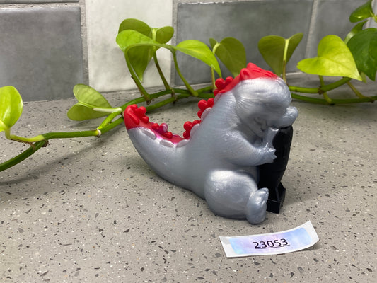 a small silver elephant figurine sitting on a counter next to a plant