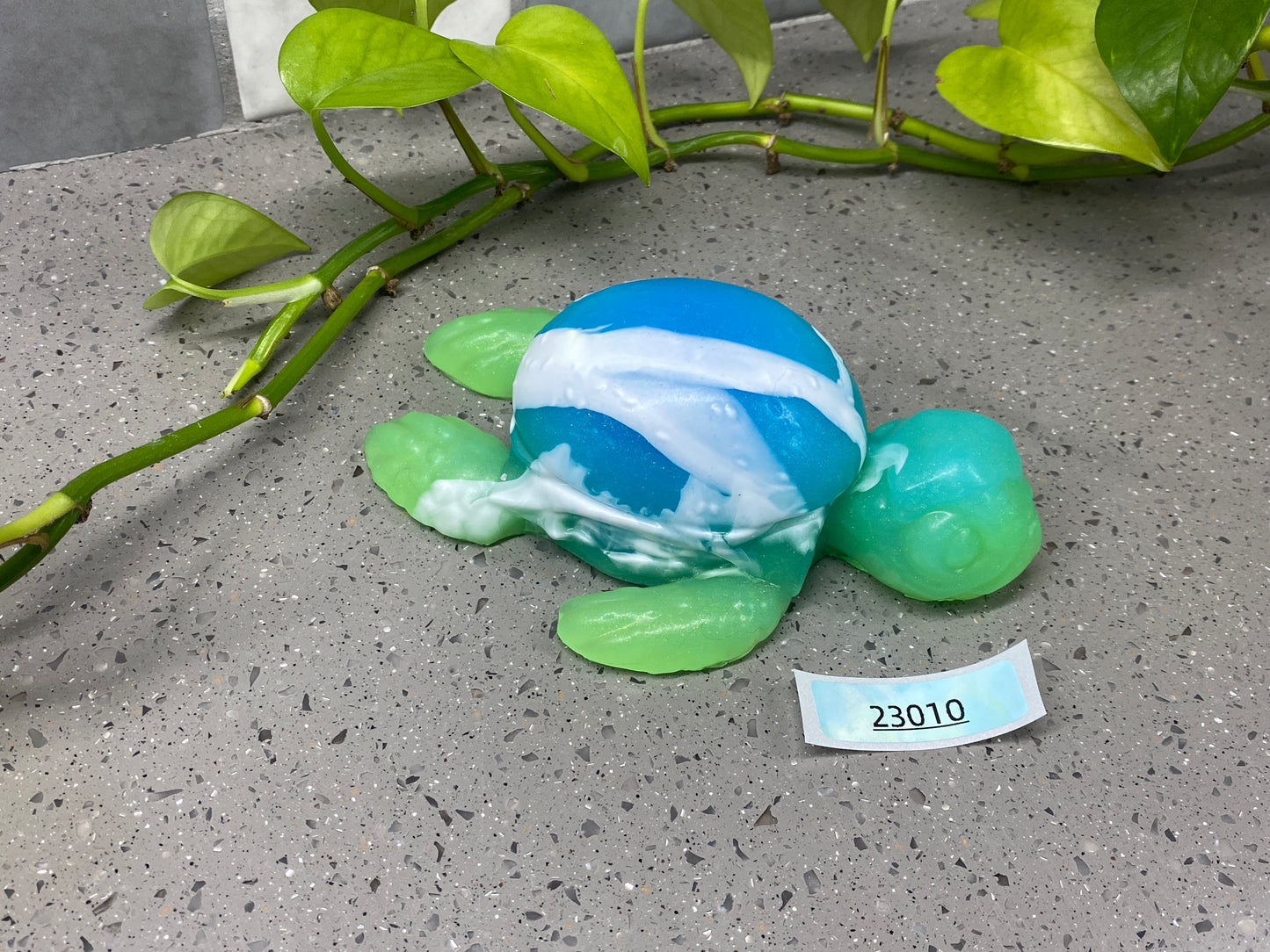 a blue and green turtle sitting on top of a cement ground