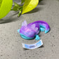 a purple and blue toy laying on top of a cement ground