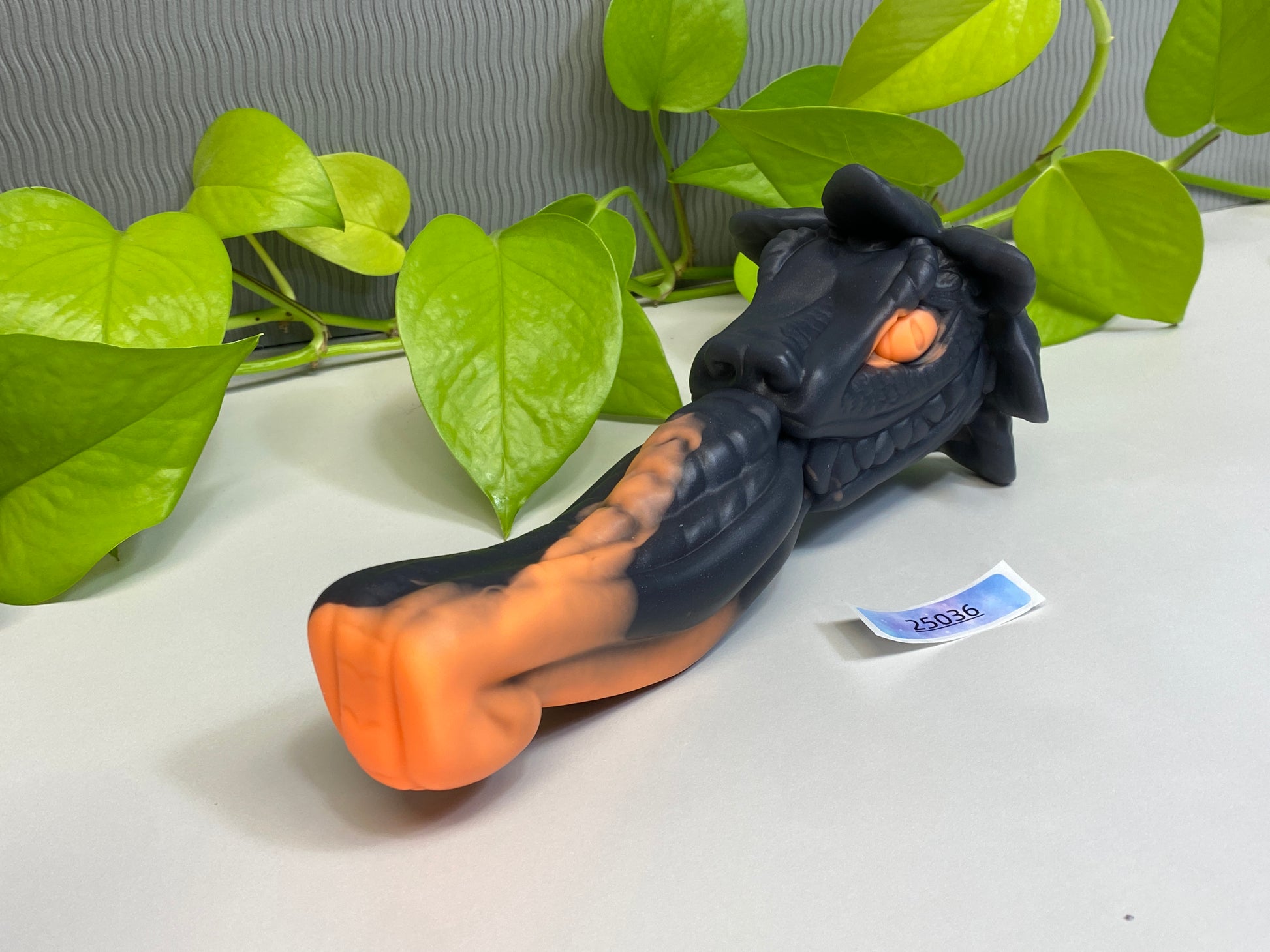 a toy of a dragon laying on a table next to a plant