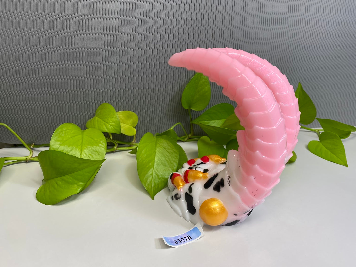 a ceramic figurine of a cow sitting on a table next to a plant