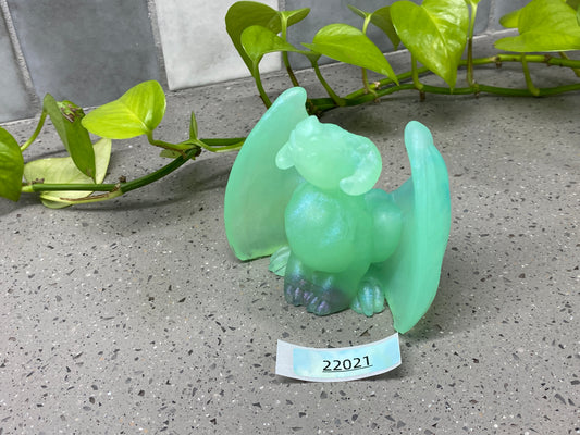 a glass figurine of a green dragon sitting on the ground