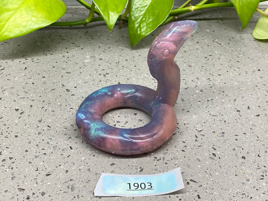 a purple ring sitting on top of a cement floor next to a plant