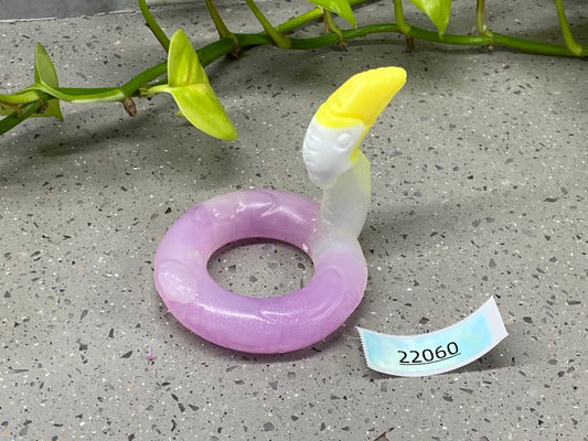 a purple and white ring sitting next to a plant