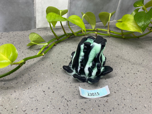 a frog figurine sitting on a table next to a plant