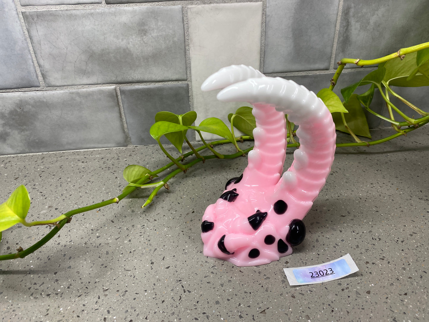 a pink and white giraffe shaped object next to a plant