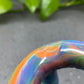 a close up of a colorful object with a plant in the background