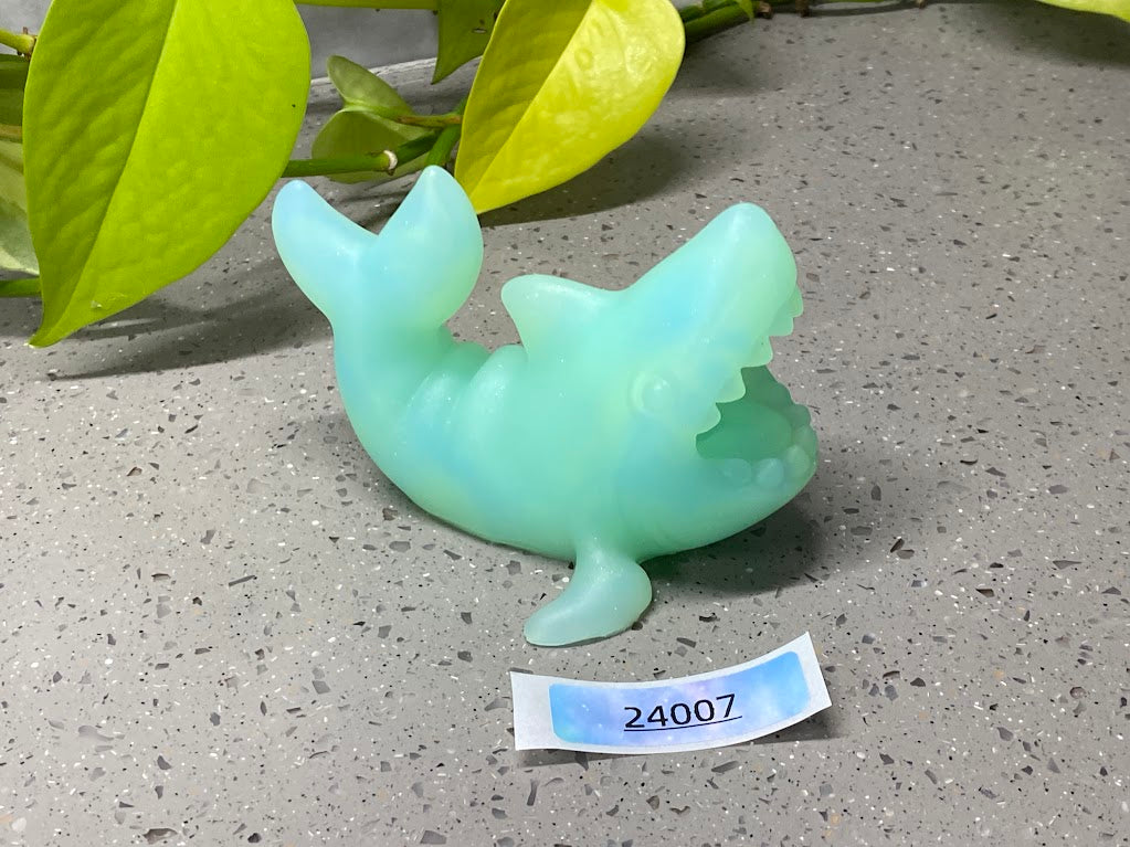 a green plastic toy sitting on top of a cement ground