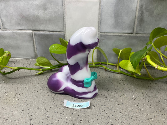 a purple and white snake figurine sitting on the ground