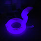 a dark room with a purple light on a toilet