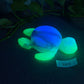 a glowing turtle on the ground next to a plant