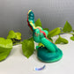 a toy snake sitting on top of a green plant