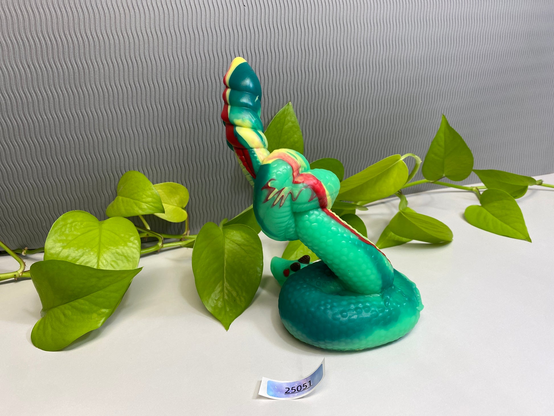 a toy snake sitting on top of a green plant