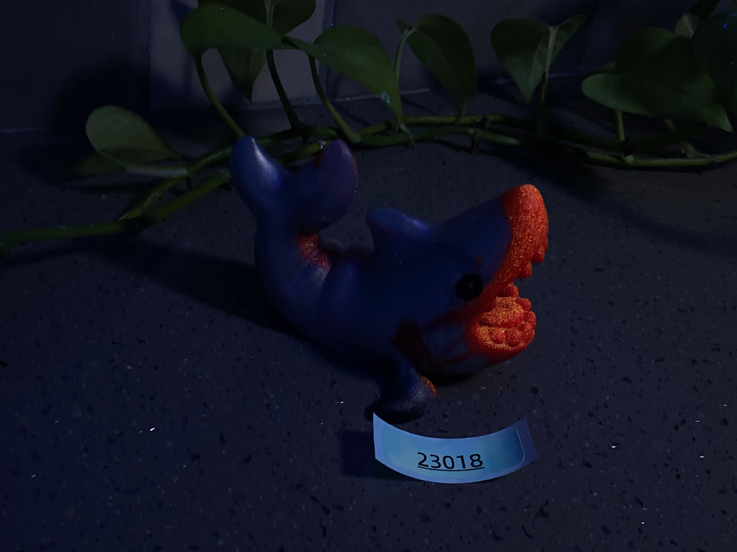 a blue elephant figurine sitting on a table next to a plant