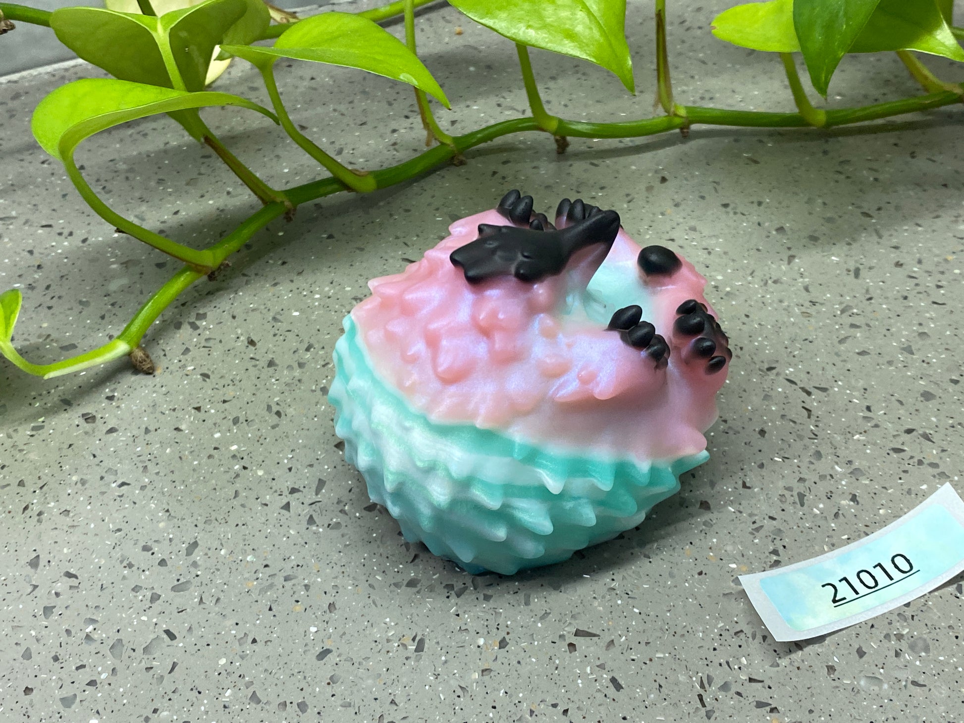 a small cupcake sitting on the ground next to a plant