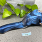 a blue statue of a cat laying on the ground next to a plant