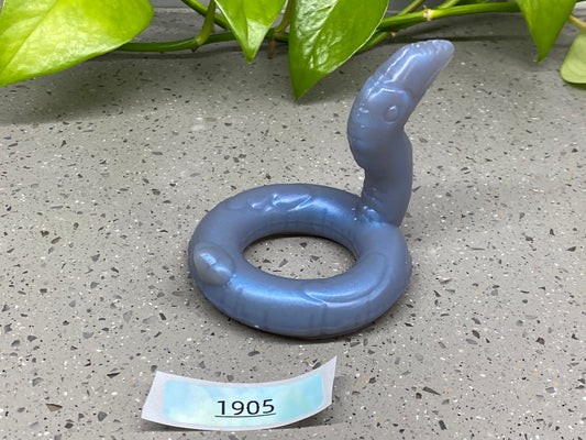 a blue object sitting on the ground next to a plant
