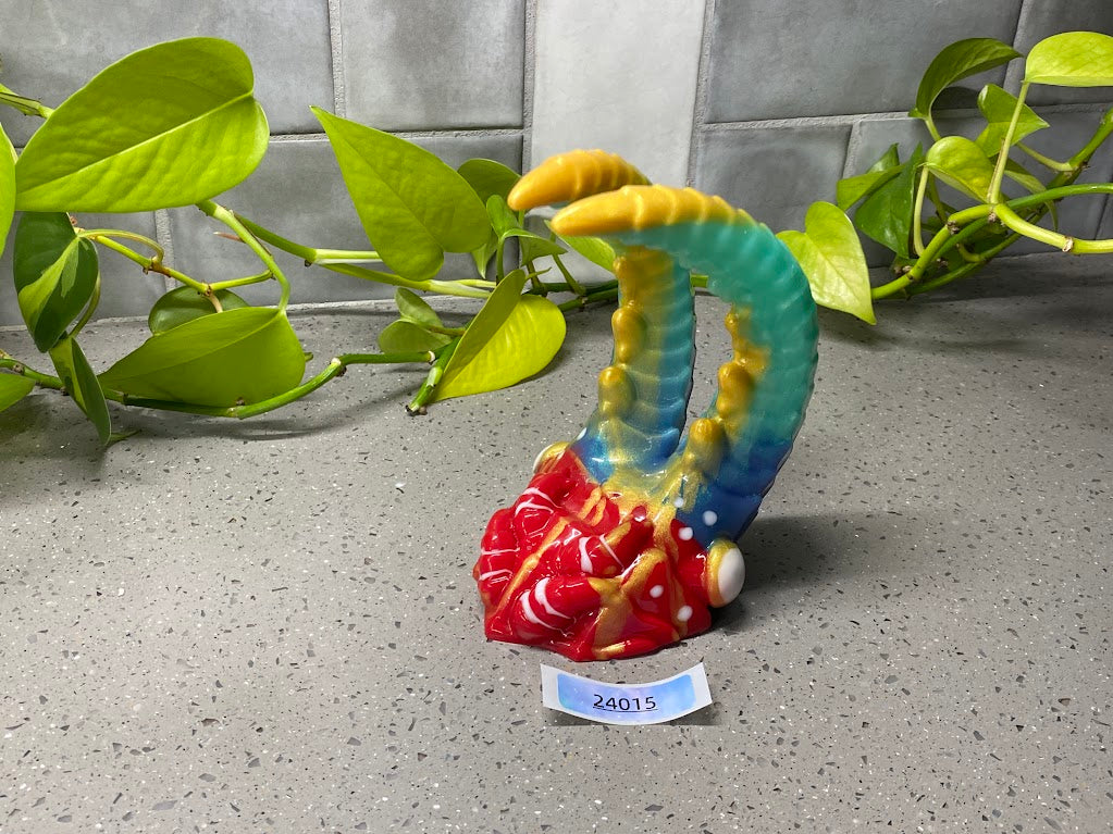 a colorful figurine sitting on top of a table next to a plant