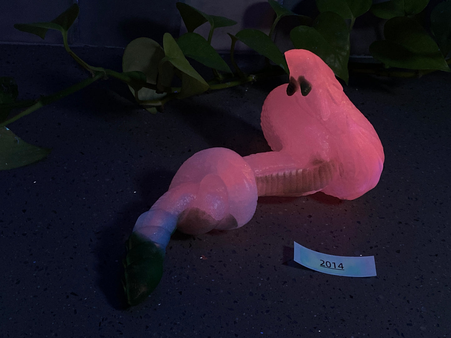 a pink plastic toy laying on a table next to a plant